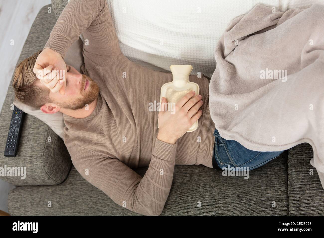 sick man lying on sofa checking his temperature at home Stock Photo Alamy