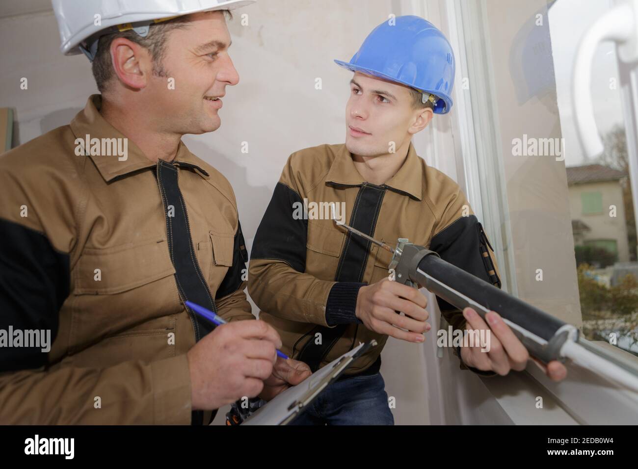 technician and apprentice using a silicon gun Stock Photo