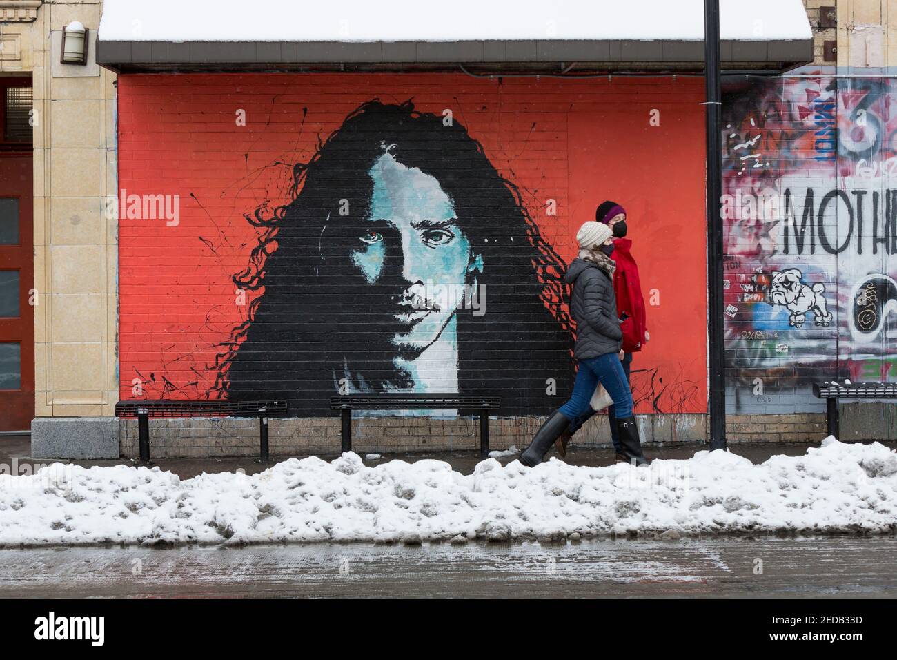 Seattle, Washington, USA. 14th February, 2021. A couple walks past a mural of Soundgarden’s Chris Cornell at Easy Street Records in West Seattle as a winter storm continues. Credit: Paul Christian Gordon/Alamy Live News Stock Photo