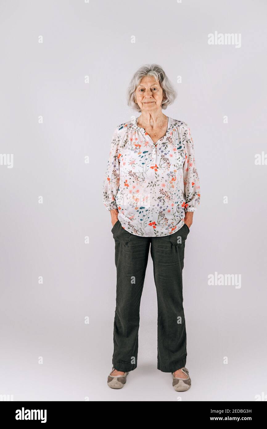 Elderly woman in her 80's with Gray hair standing isolated on a white backdrop Stock Photo