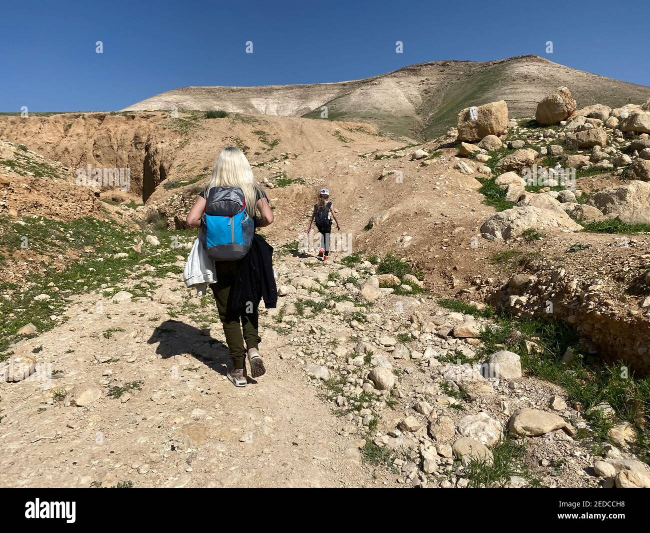 Mother with kid hiking in mountains. Young tourists on top of a mountain enjoying valley view before sunset Stock Photo