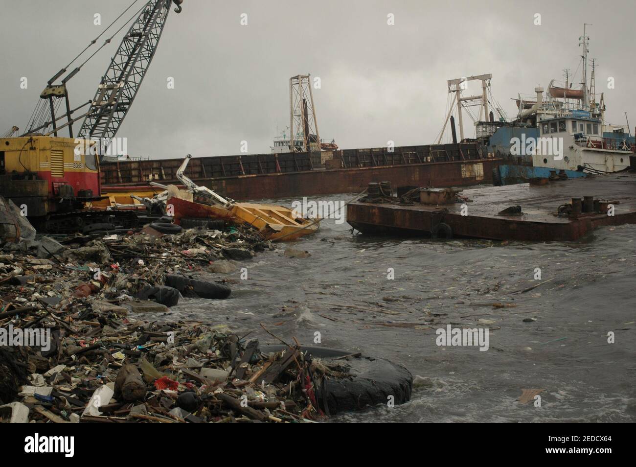 Litters on coastal environment that are landed by waves, and parts of broken ships partly floating on coastal water; a view on a rainy day at a ship-breaking yard in Kalibaru, Cilincing, Jakarta, Indonesia (2005). Stock Photo