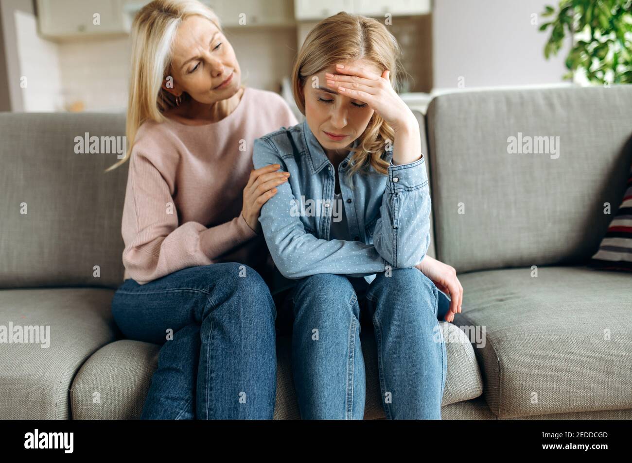 Worried mature mother consoles her adult daughter, helping with problem and depression, caring she, empathy, support in two age generations. Support of a loved one Stock Photo