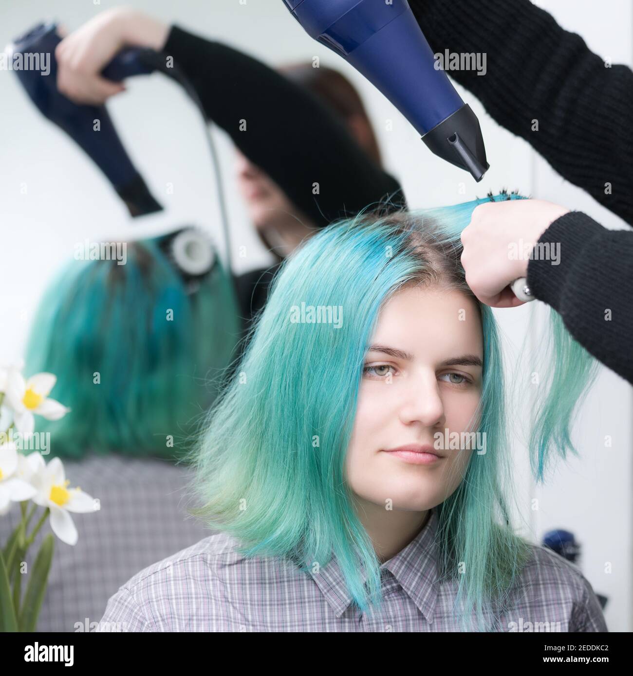 Portrait of beautiful young woman with long green hair while drying and styling hair in beauty