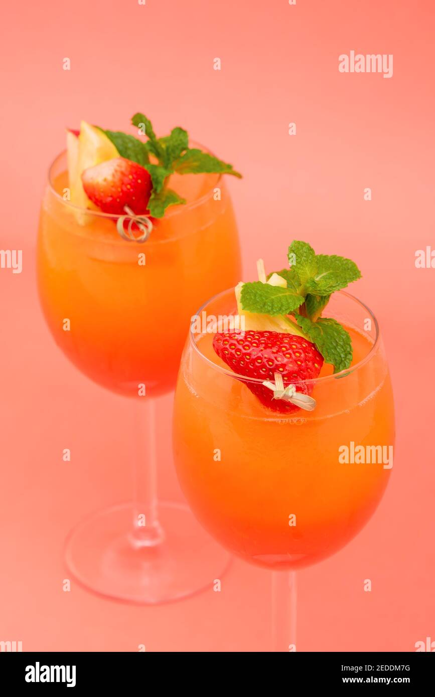 Colorful refreshing strawberry orange sunrise cocktail drinks in the glasses on coral pink background Stock Photo