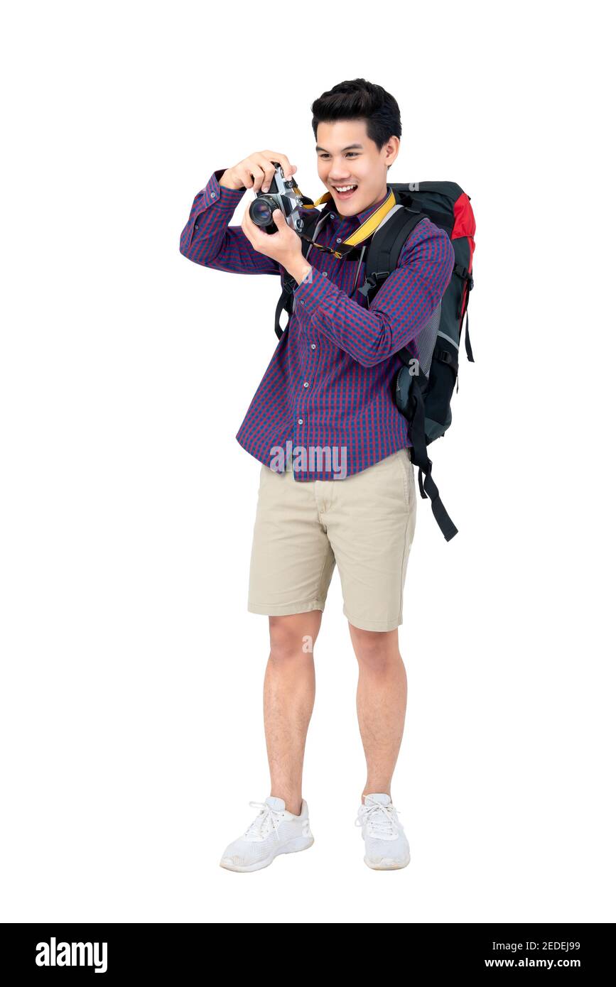Isolated Portrait of happy young attractive asian tourist man in casual attire carrying a backpack taking a photo with his camera Stock Photo