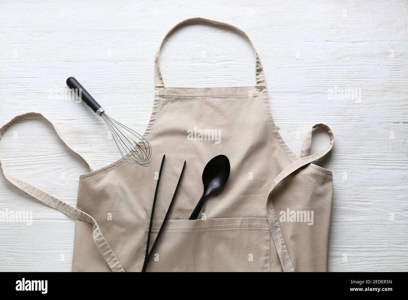 Clean apron and kitchen utensils on light wooden background Stock Photo ...