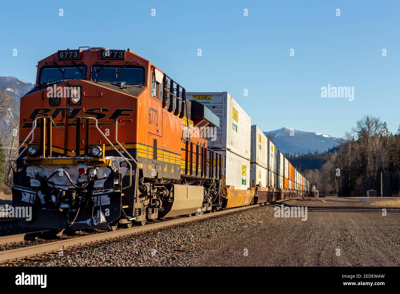 A trailing push locomotive, 6773, of a BNSF intermodal shipping container freight train coming down the tracks in the town of Troy, Montana. Stock Photo