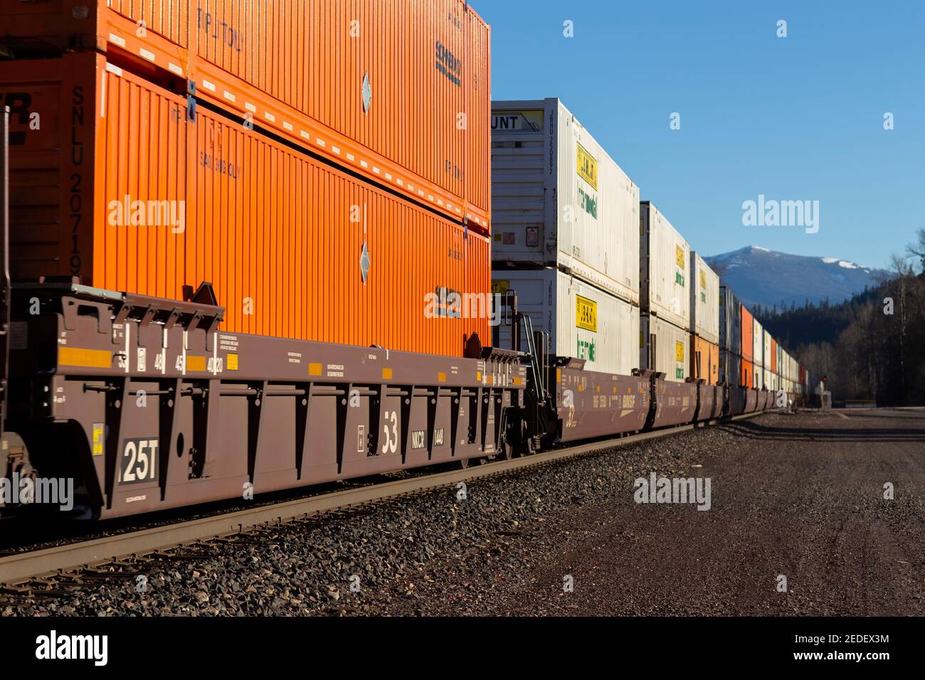 A line of shipping container well cars rolling through the BNSF rail yard in Troy, Montana.   Burlington Northern and Santa Fe Railway was formed in 1 Stock Photo