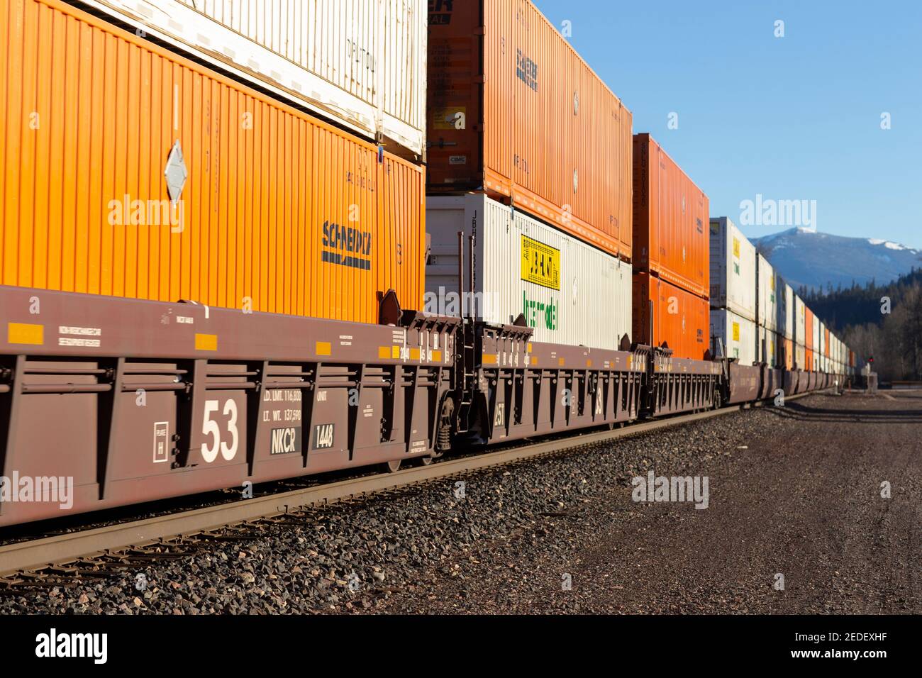 A line of shipping container well cars rolling through the BNSF rail yard in Troy, Montana.   Burlington Northern and Santa Fe Railway was formed in 1 Stock Photo