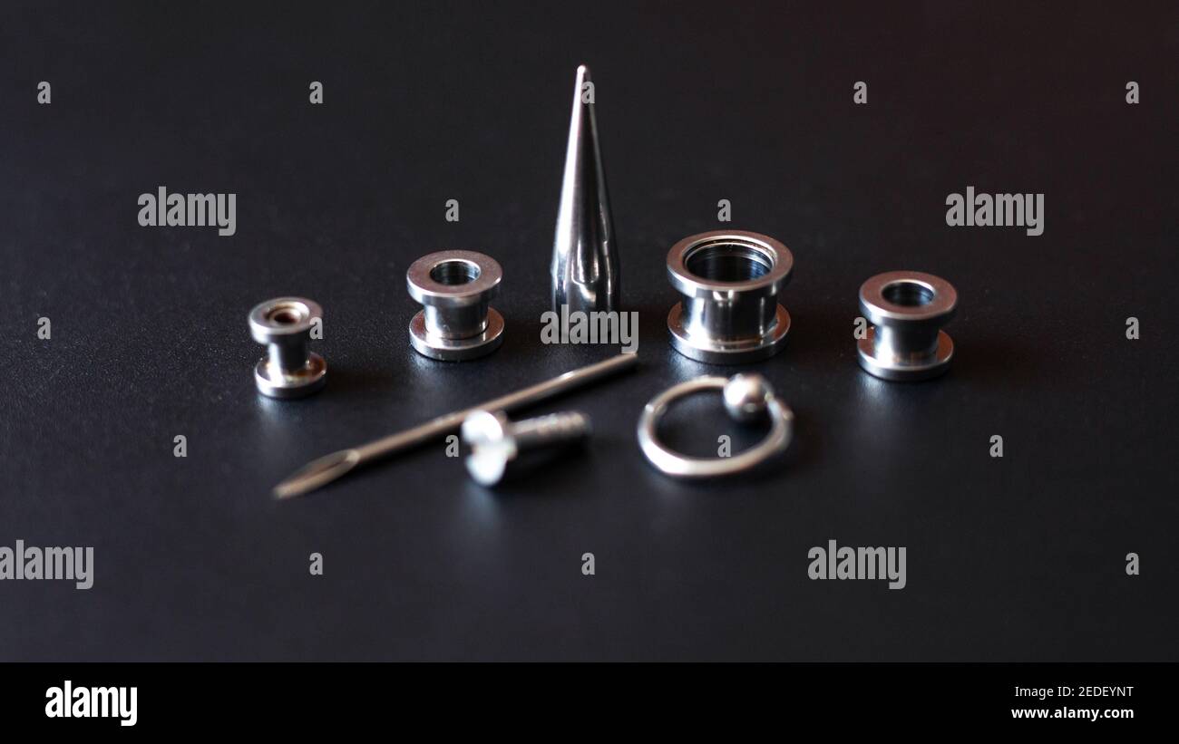 Set for piercing on a dark background, ear tunnels, tunnels and earrings for the ears and tongue