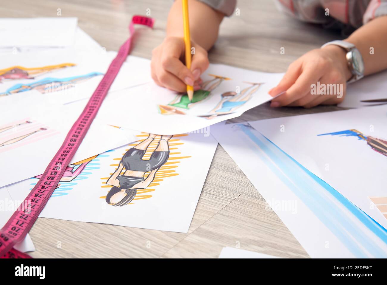 Female fashion designer working with sketches on floor in studio Stock ...
