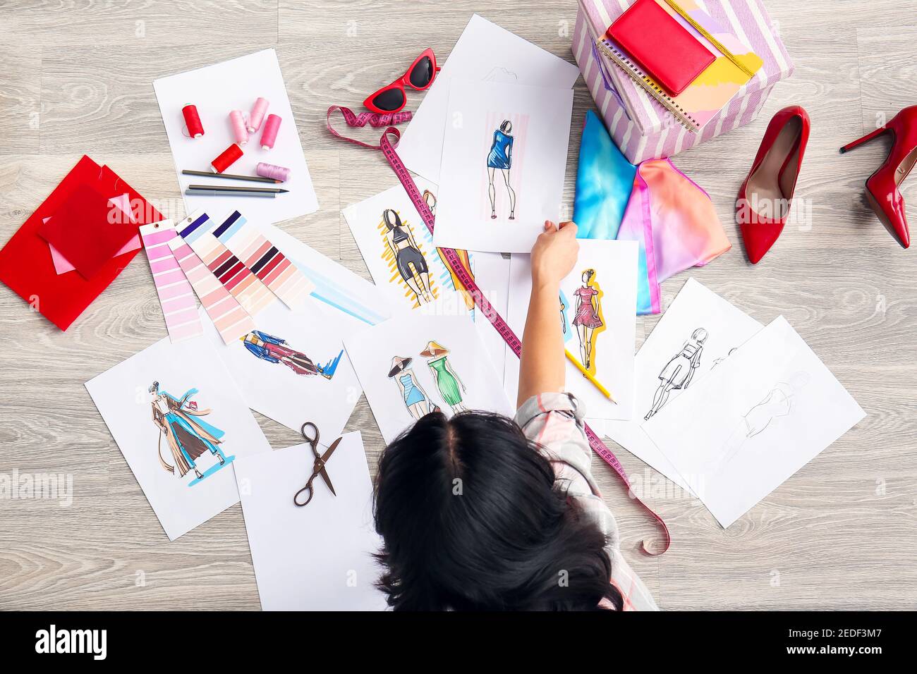 Female fashion designer working with sketches on floor in studio Stock ...