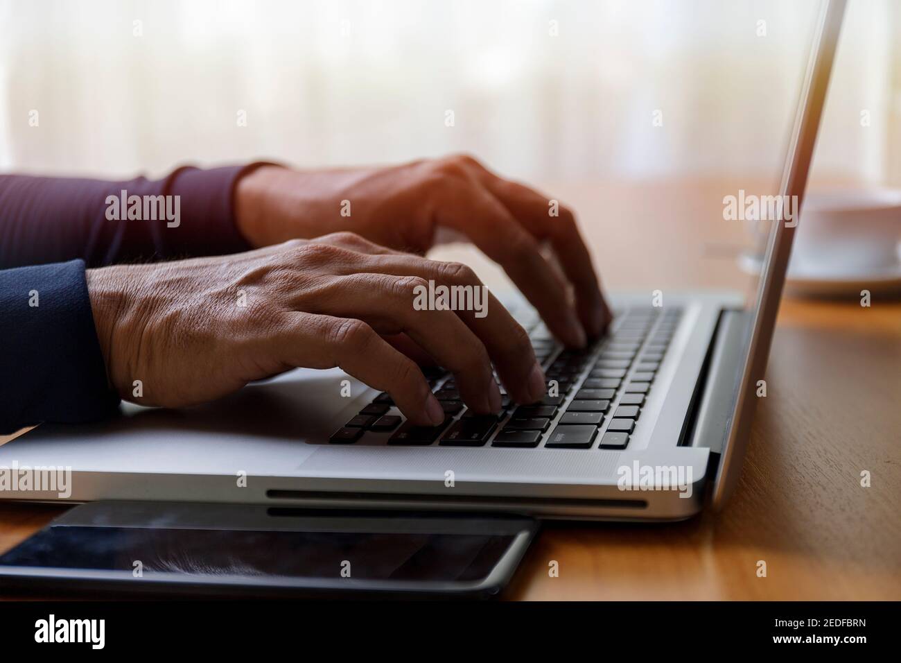 Close up businessman using laptop computer at home. Close up male hands typing on laptop keyboard in office. Man hands using laptop keyboard. Close-up Stock Photo
