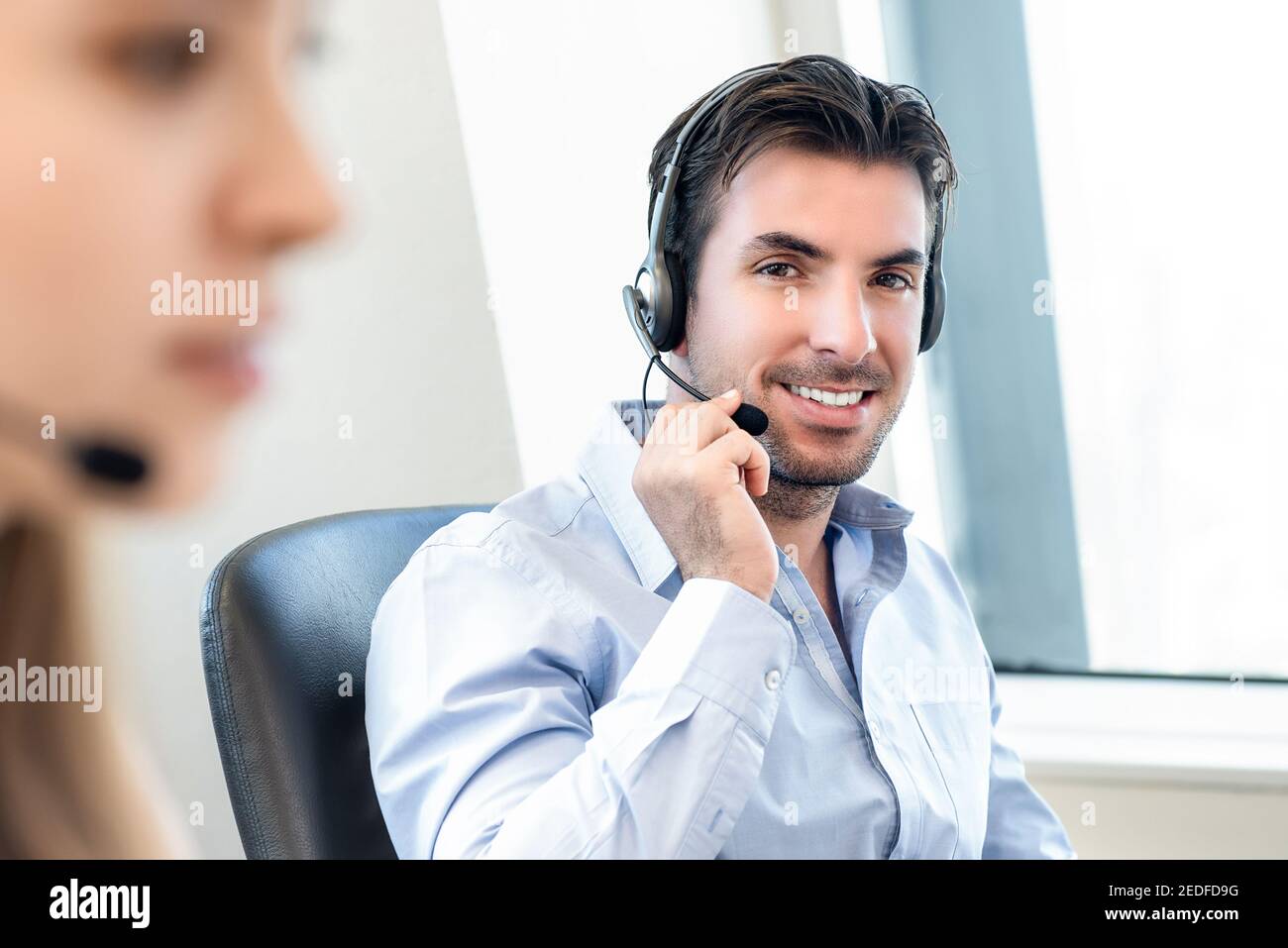 Smiling friendly Hispanic man working in call center office as a telemarketing customer service agent Stock Photo