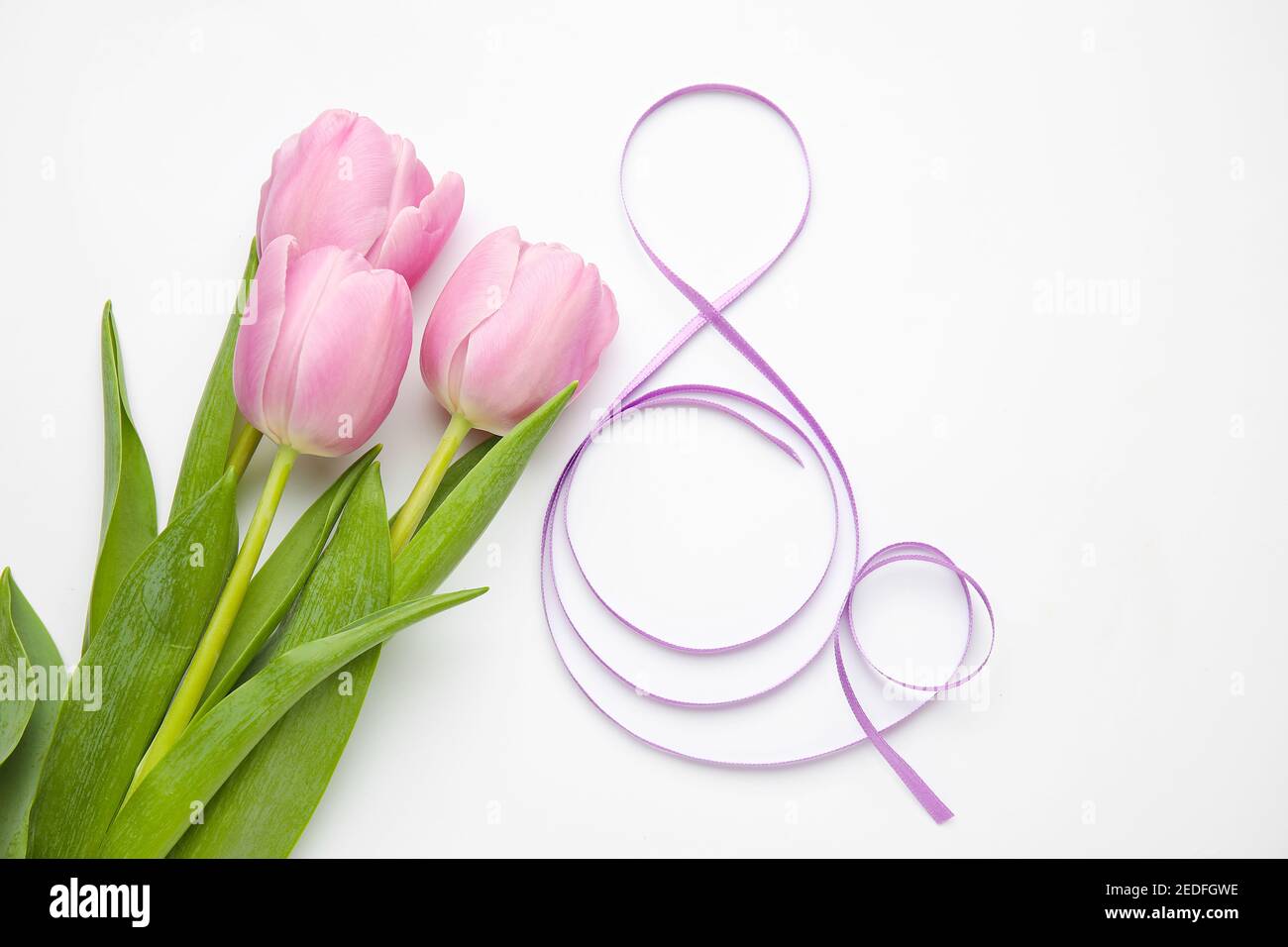 Figure 8 made of violet ribbon and tulip flowers on light background ...