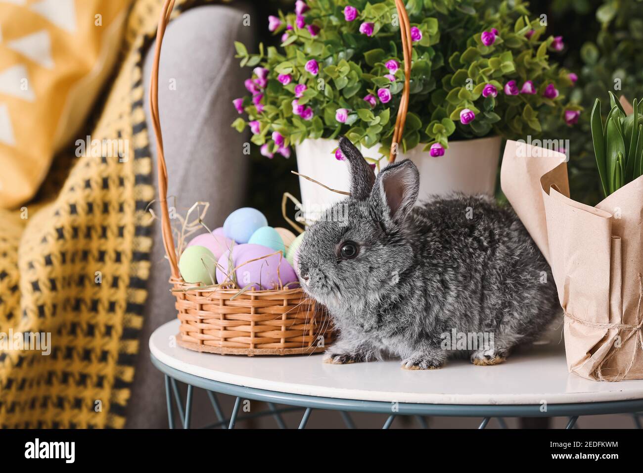 Cute rabbit and basket with Easter eggs on table Stock Photo - Alamy