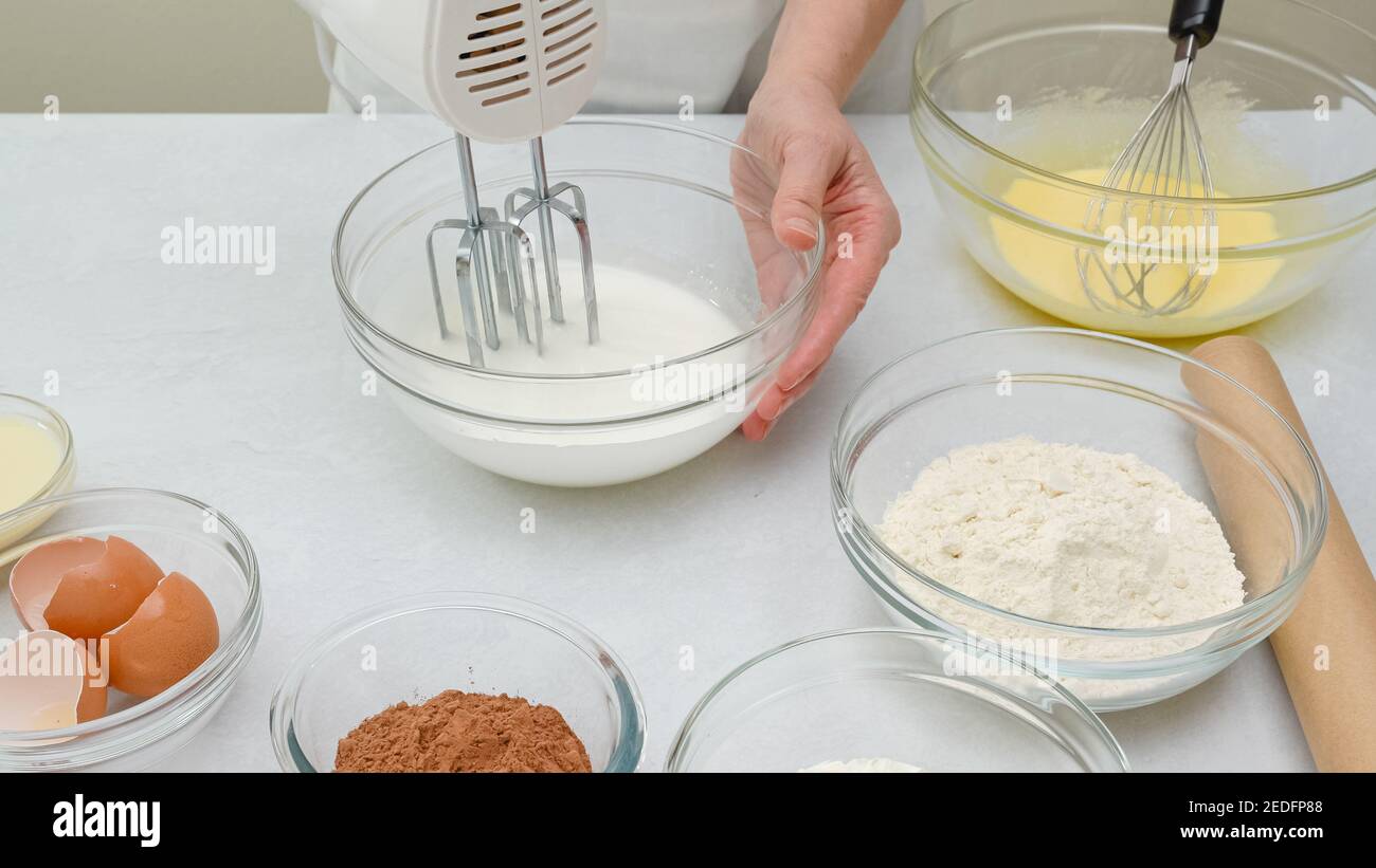 Chocolate cake step by step recipe. Woman hands beating egg whites with