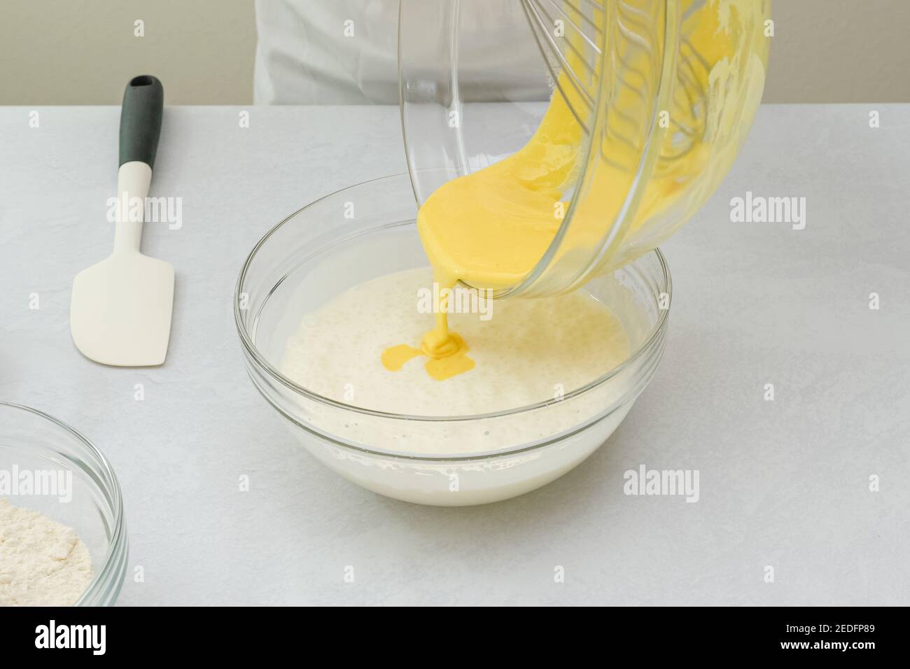 Whisked egg whites and egg yolks mixing together in a glass bowl