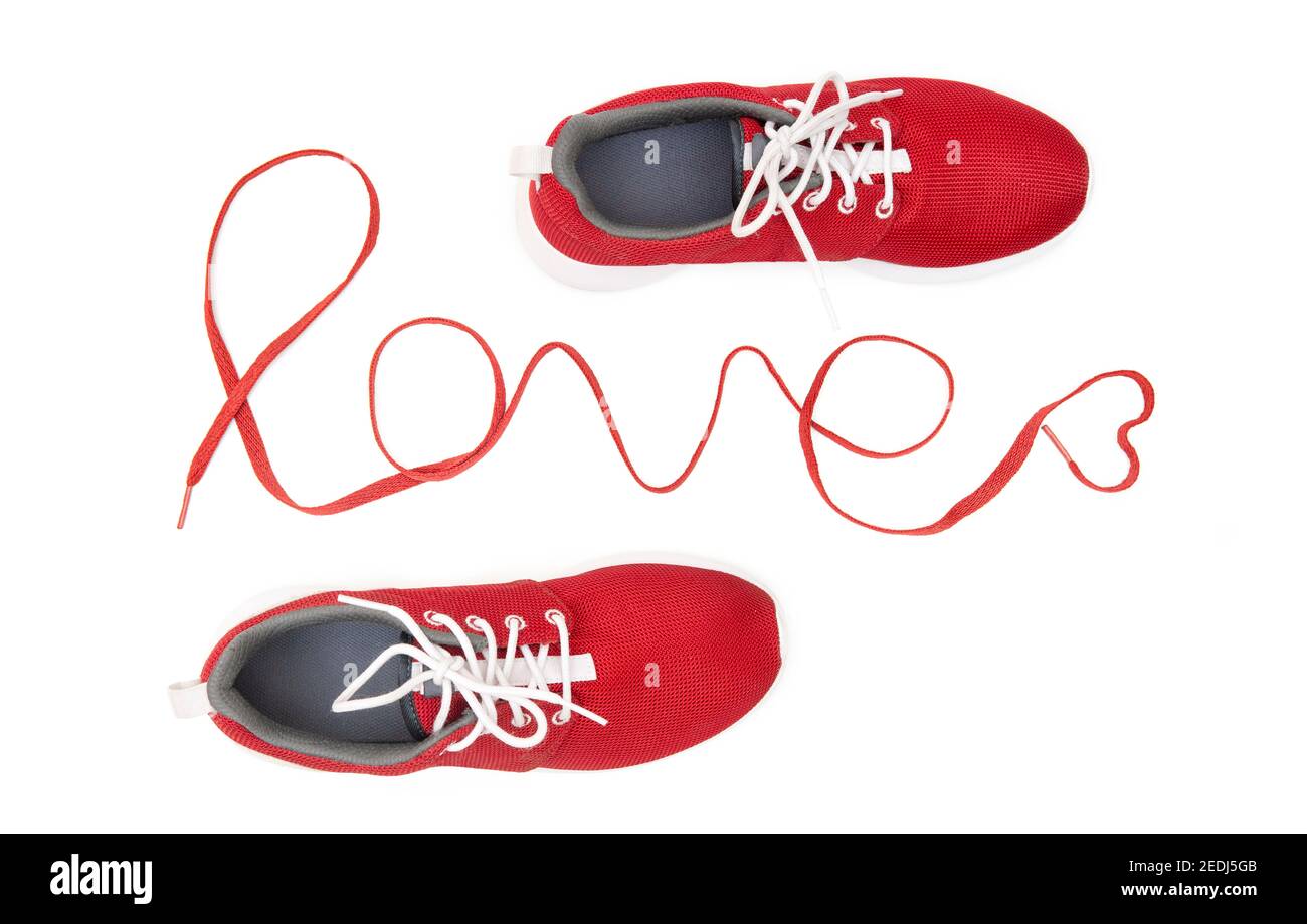 Red running sneakers and lettering 'love' made of athletic shoelaces isolated on white background. Active lifestyle motivational concept. Stock Photo