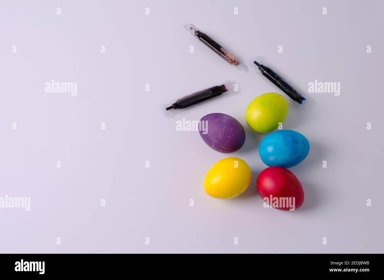 Easter background. Painted chicken eggs in yellow, green, blue, red, purple colors lie on a light background. Step 5 Stock Photo