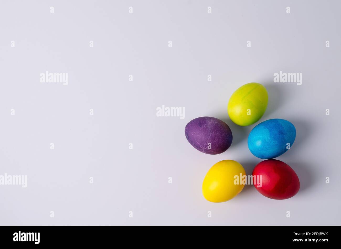 Easter background. Painted chicken eggs in yellow, green, blue, red, purple colors lie on a light background. Step 5 Stock Photo