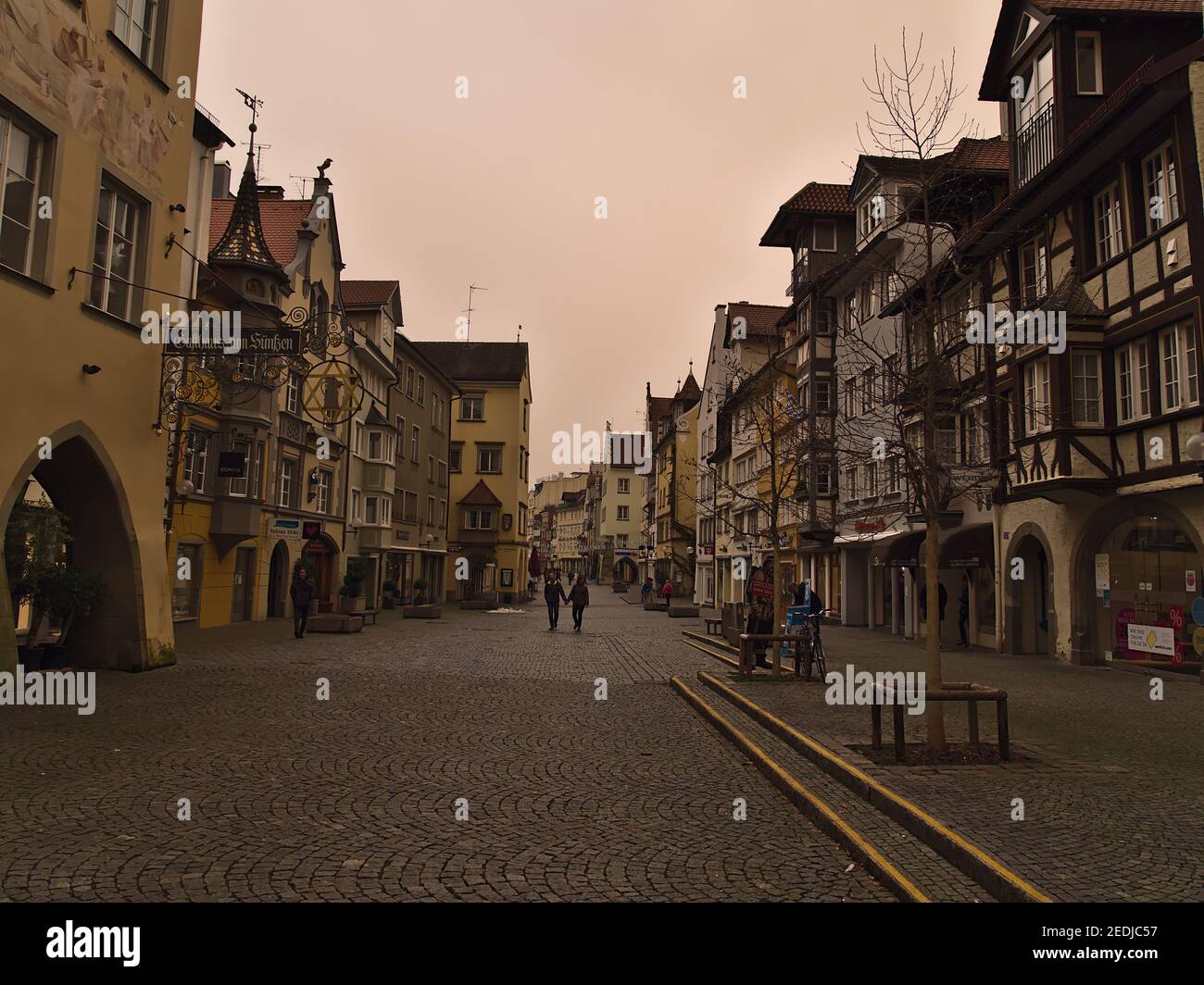 Pedestrian zone in historic town center on cloudy winter day. Orange colored sky due to rare weather phenomenon (Sahara desert sand in air). Stock Photo