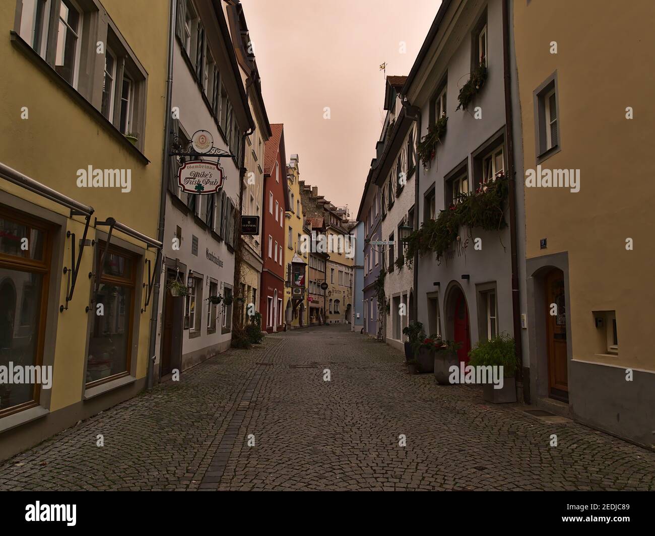 Empty alley with old buildings in town center on cloudy winter day. Orange colored sky due to weather phenomenon (Sahara desert sand in air). Stock Photo