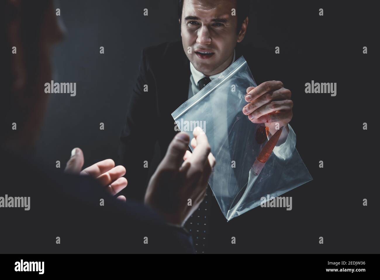 Police in interrogation room showing a knife with blood as a murder evidence, crime investigation concept Stock Photo