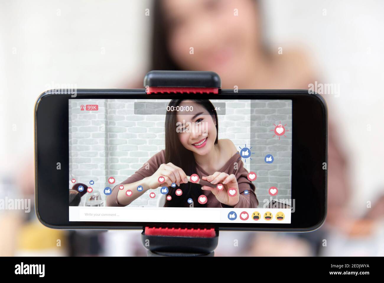Asian woman professional beauty vlogger or blogger live broadcasting cosmetic makeup tutorial viral video clip by smartphone on social media Stock Photo