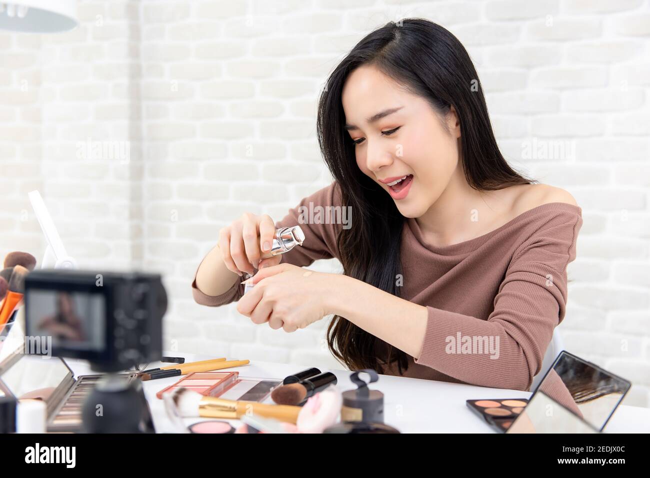Young beautiful Asian woman professional beauty vlogger or blogger live broadcasting cosmetic makeup review on social media Stock Photo