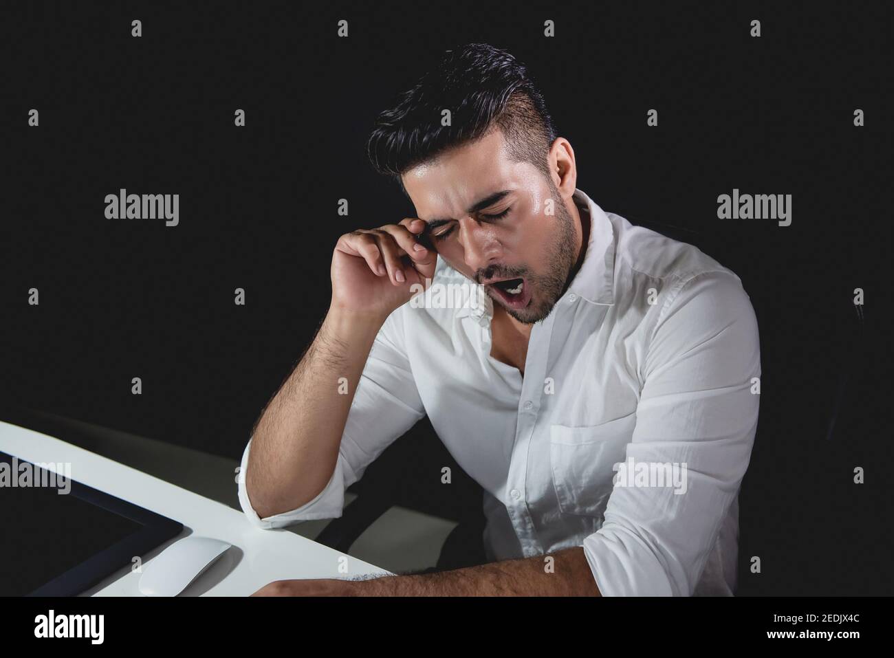 Tired fatigued Asian businessman feeling sleepy and yawning while working night shift Stock Photo