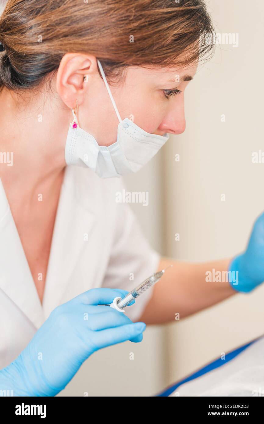 Cosmetic surgery on the skin of the face - intramuscular injection of a filler under the skin into the face of an aged woman Stock Photo