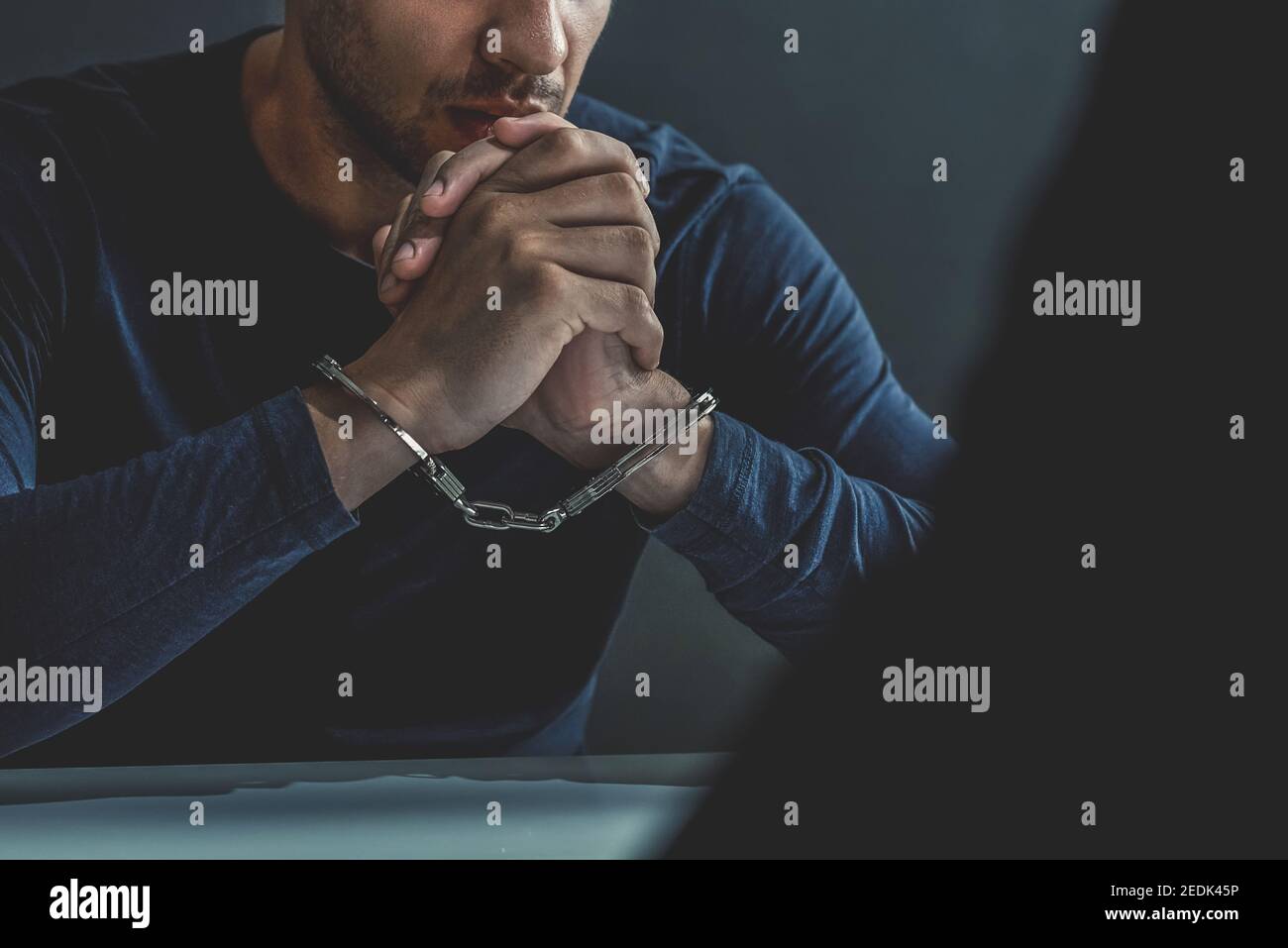Criminal man with handcuffs in interrogation room being interviewed after committed a crime Stock Photo