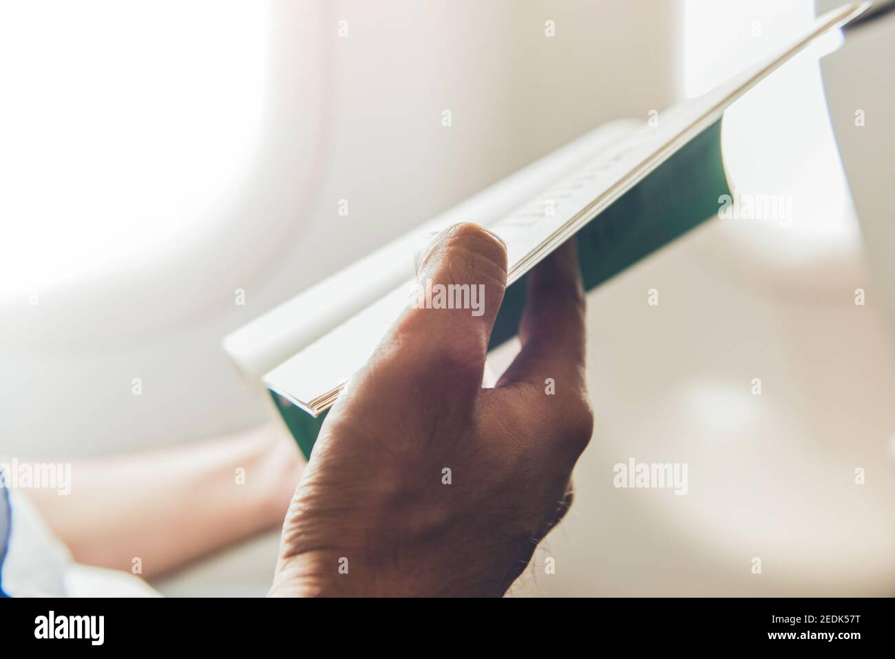 Male passenger killing time by reading book while traveling on the plane Stock Photo