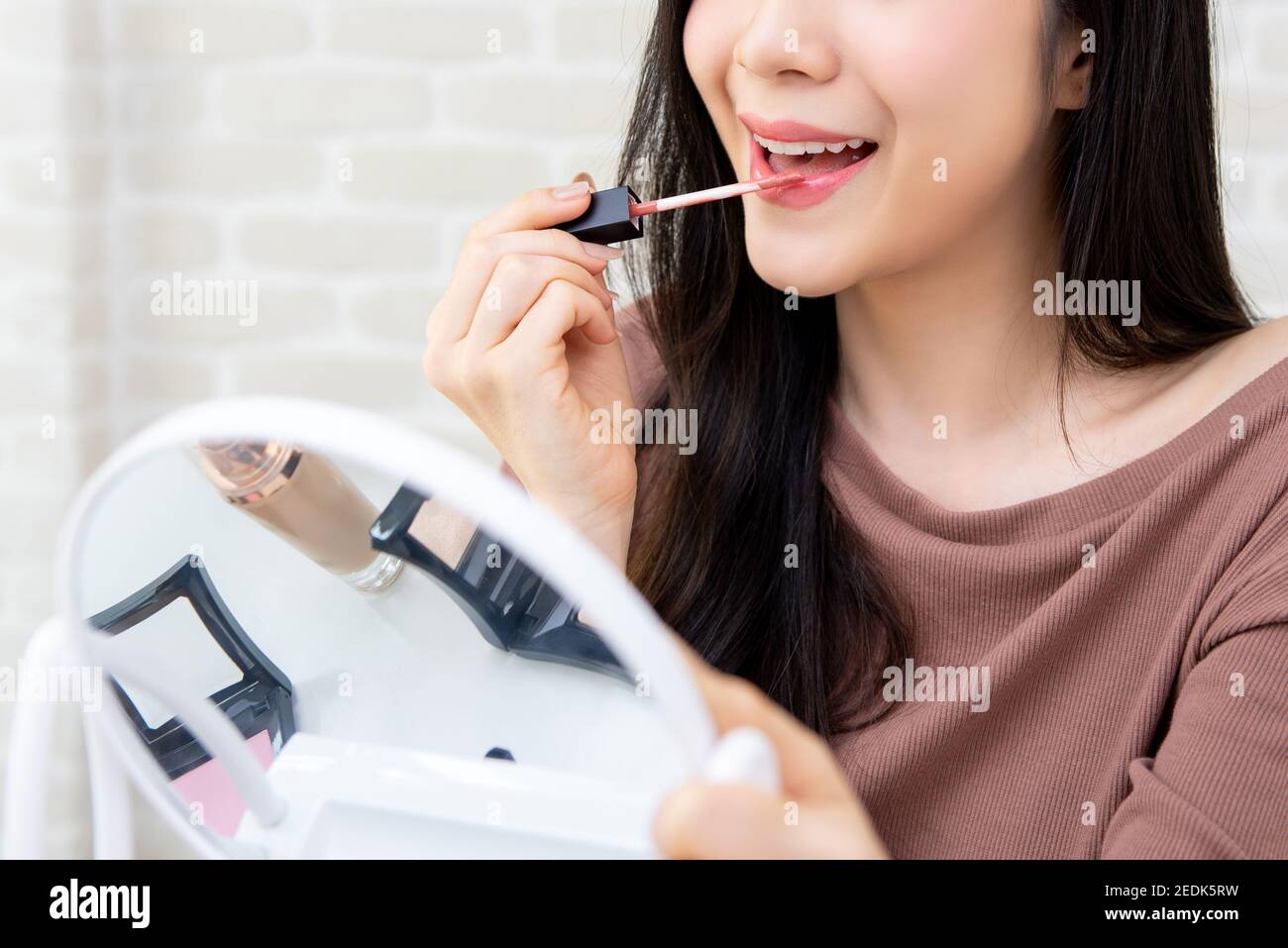 Young beautiful woman professional beauty vlogger or blogger applying lipstick cream to her mouth, doing cosmetic makeup tutorial Stock Photo