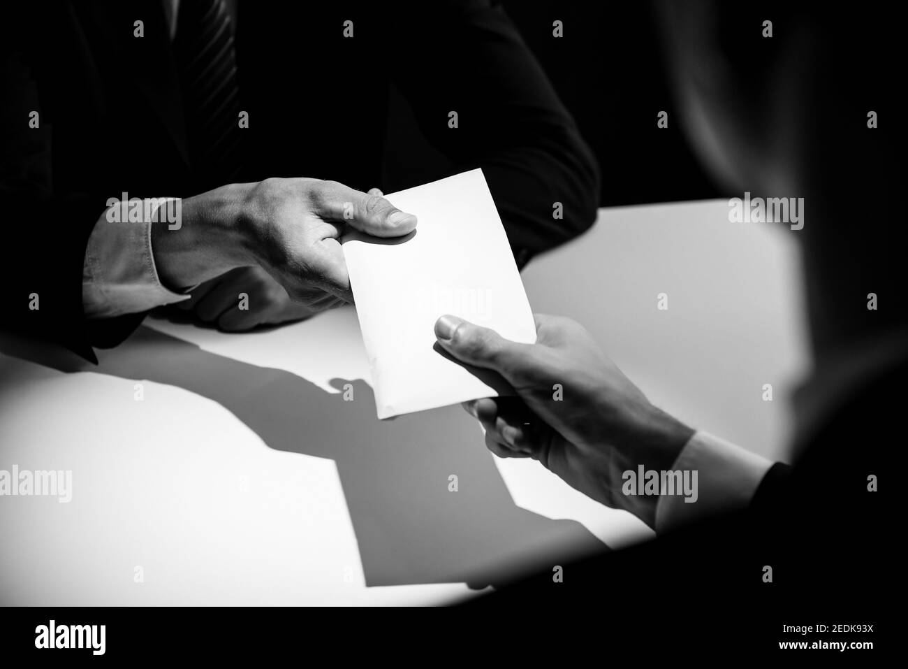 Businessman giving bribe money in the  envelope to partner in a corruption scam with black and white tone Stock Photo