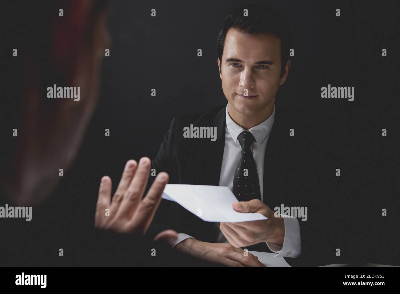 Businessman rejecting money in white envelope offered by his partner in shadow, anti bribery and corruption concept Stock Photo