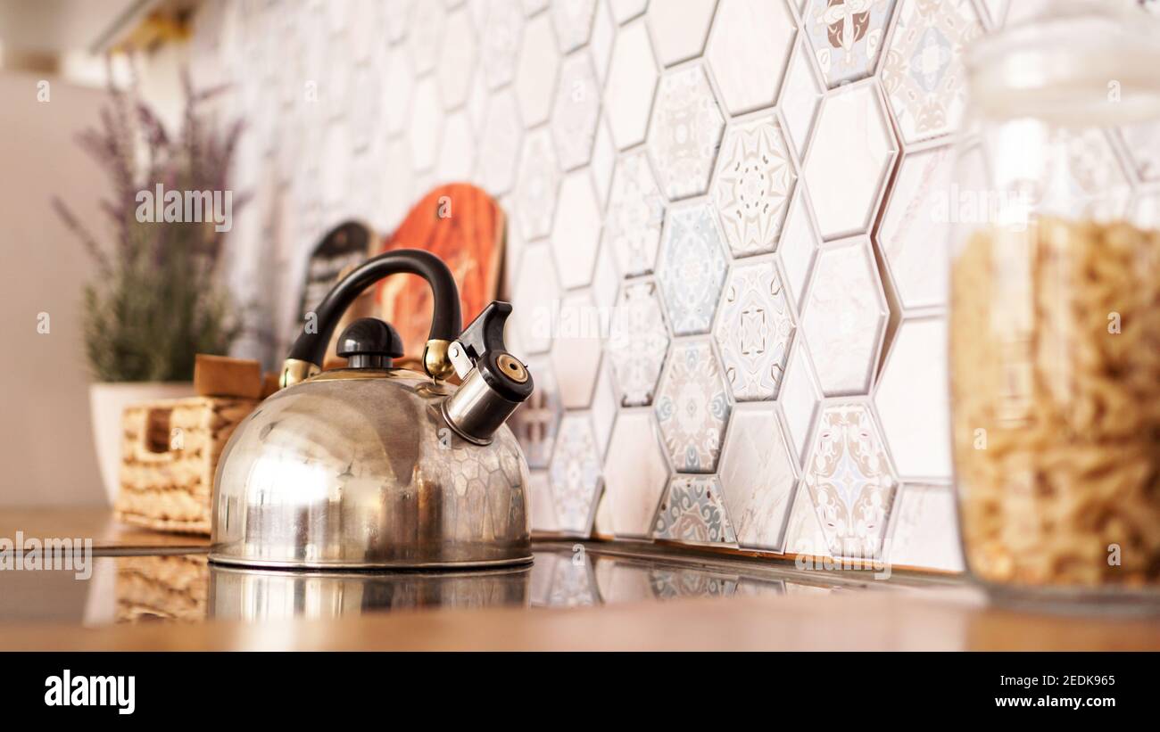 Metal kettle on the stove. Modern cozy kitchen. Stock Photo