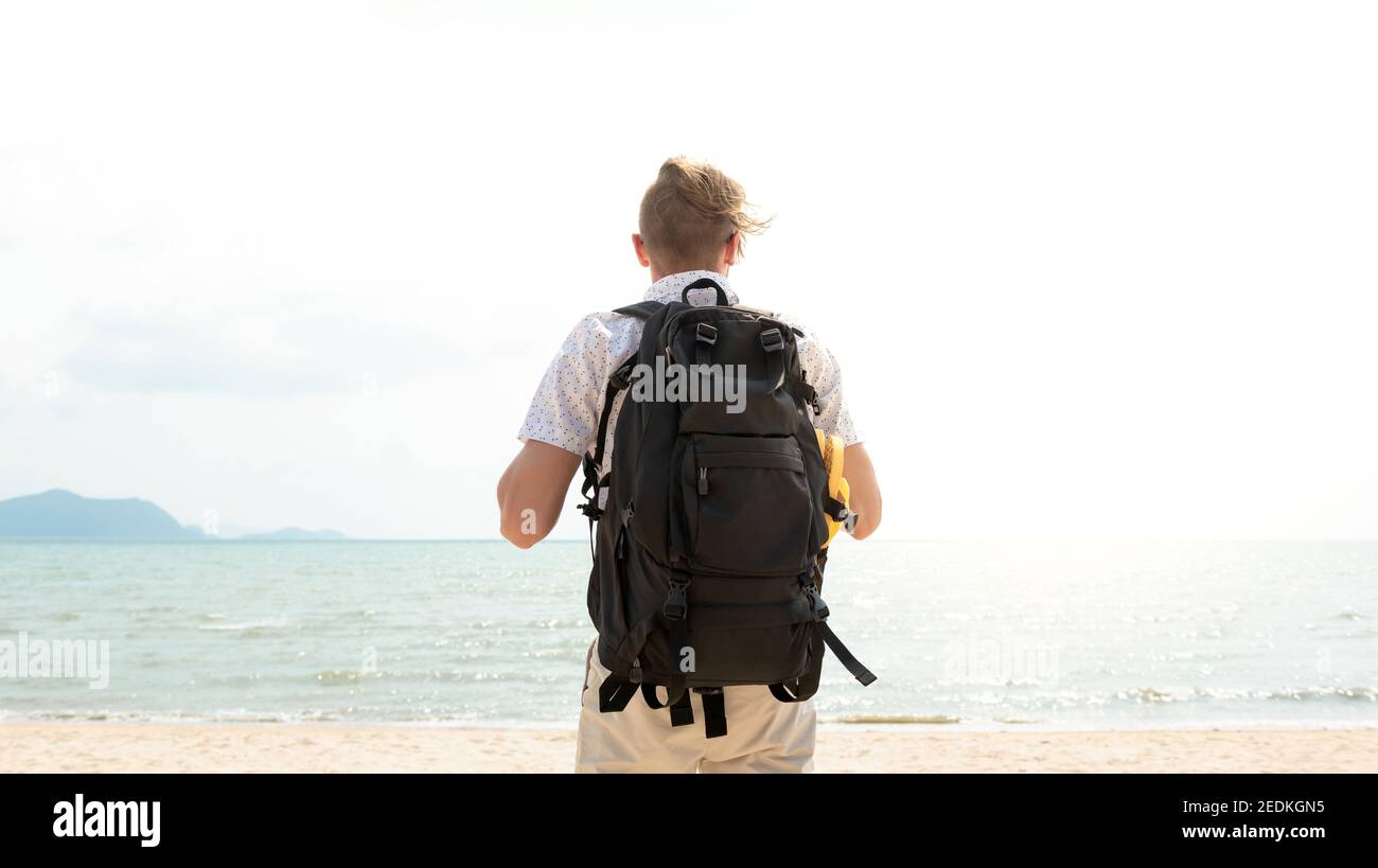 Independent young man tourist backpacker at the beach during summer vacations Stock Photo
