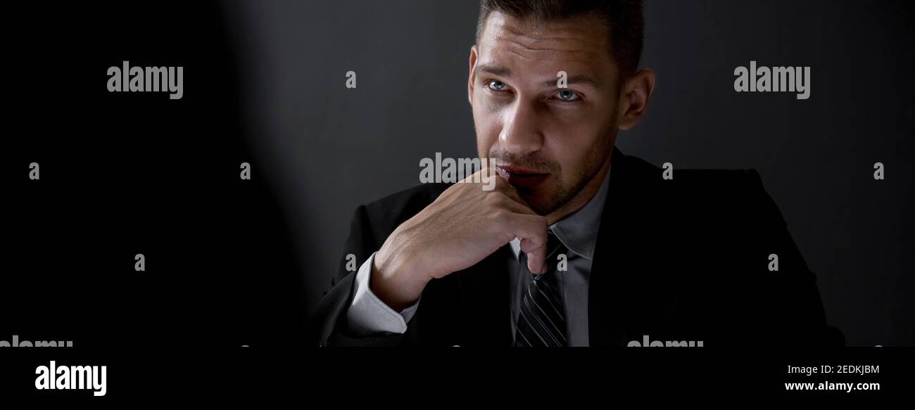 Man in shadow with serious face staring at interlocutor, criminal interrogation concept, panoramic banner Stock Photo