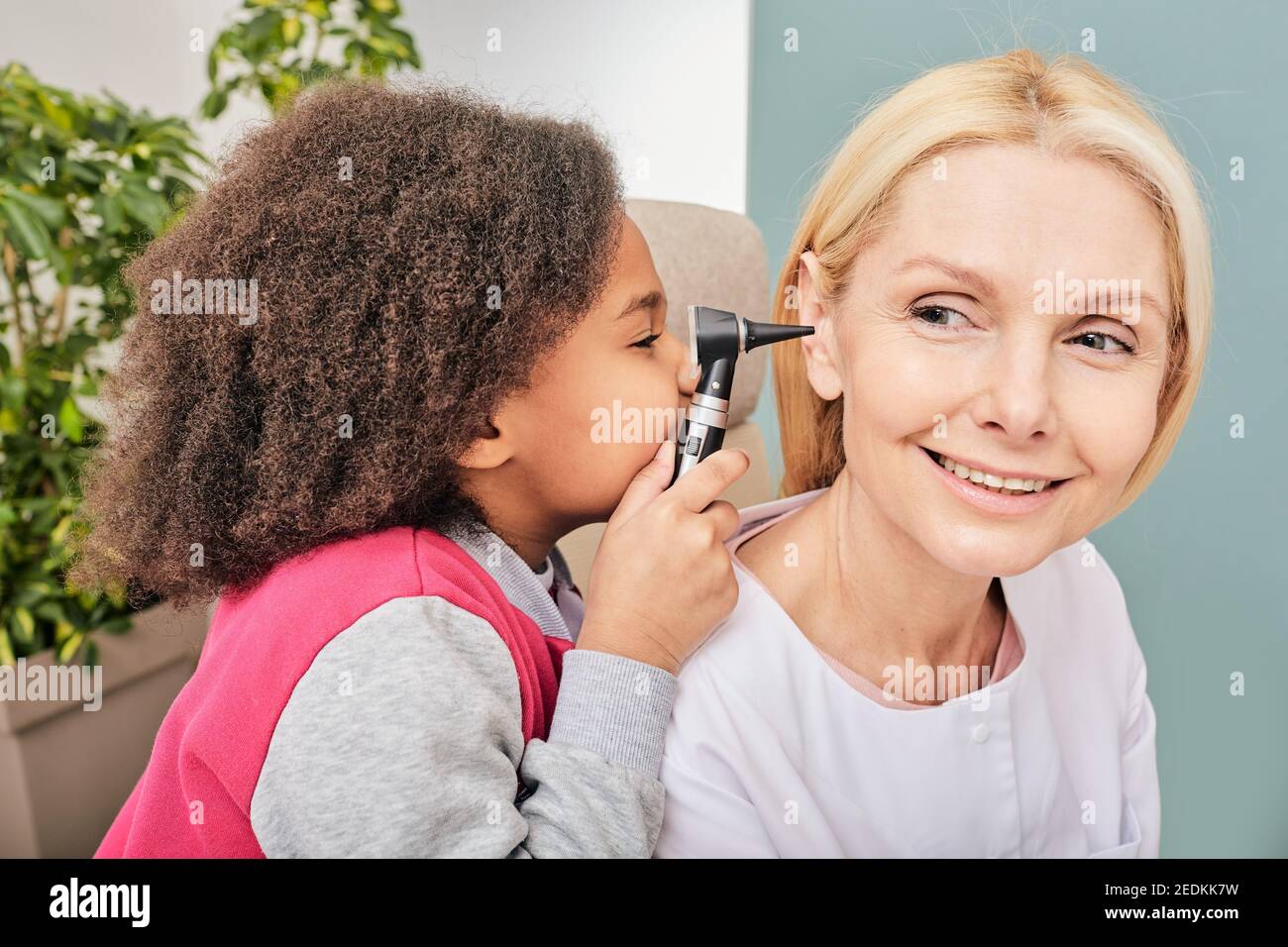 Ear exam. African little girl examining doctor with an otoscope. Treatment deafness for a child