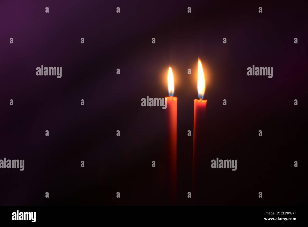 Burning candles at Night. Two red candles on dark purple background