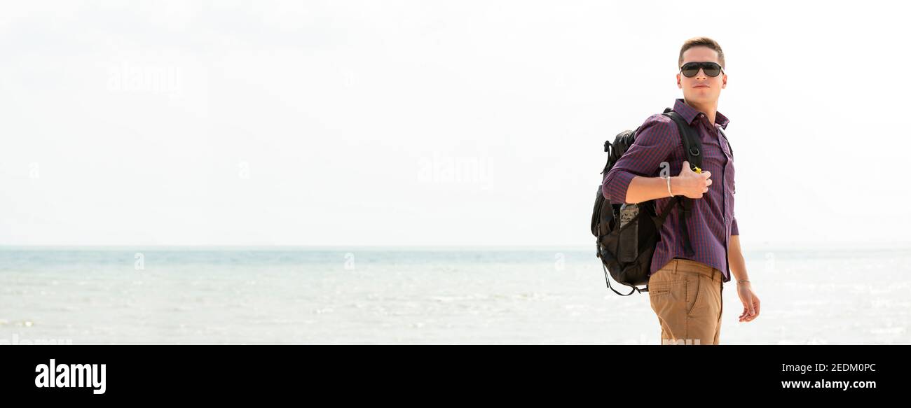 Independent man tourist backpacker at the beach on summer vacation travel, panoramic banner with copy space Stock Photo