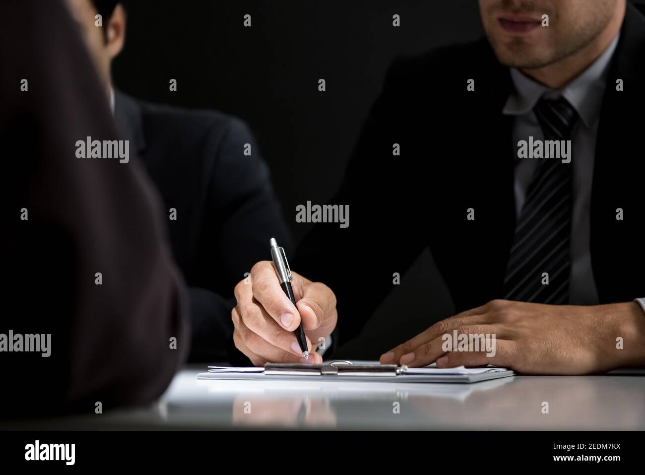 Interrogator taking note while interviewing suspect in the interrogation room Stock Photo