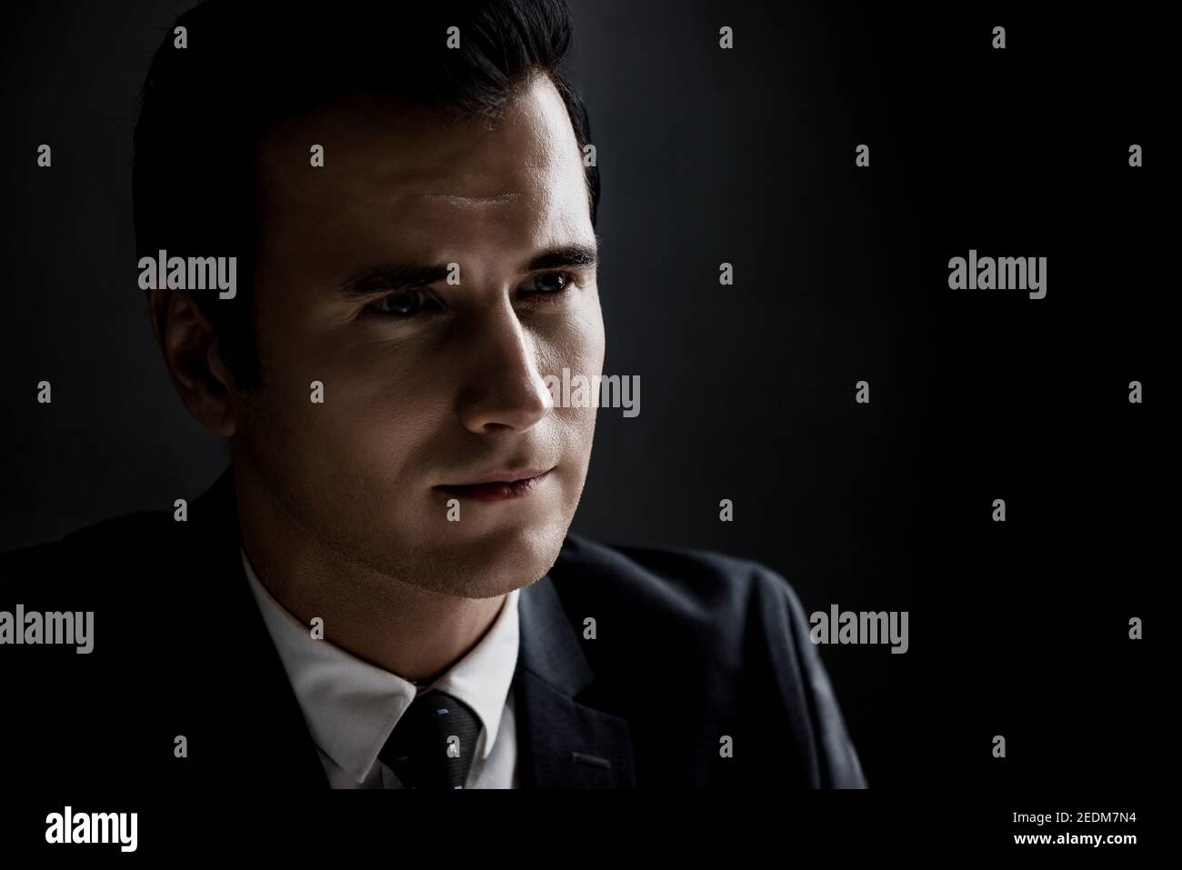 Man in shadow with serious face staring at interlocutor, criminal interrogation concept Stock Photo