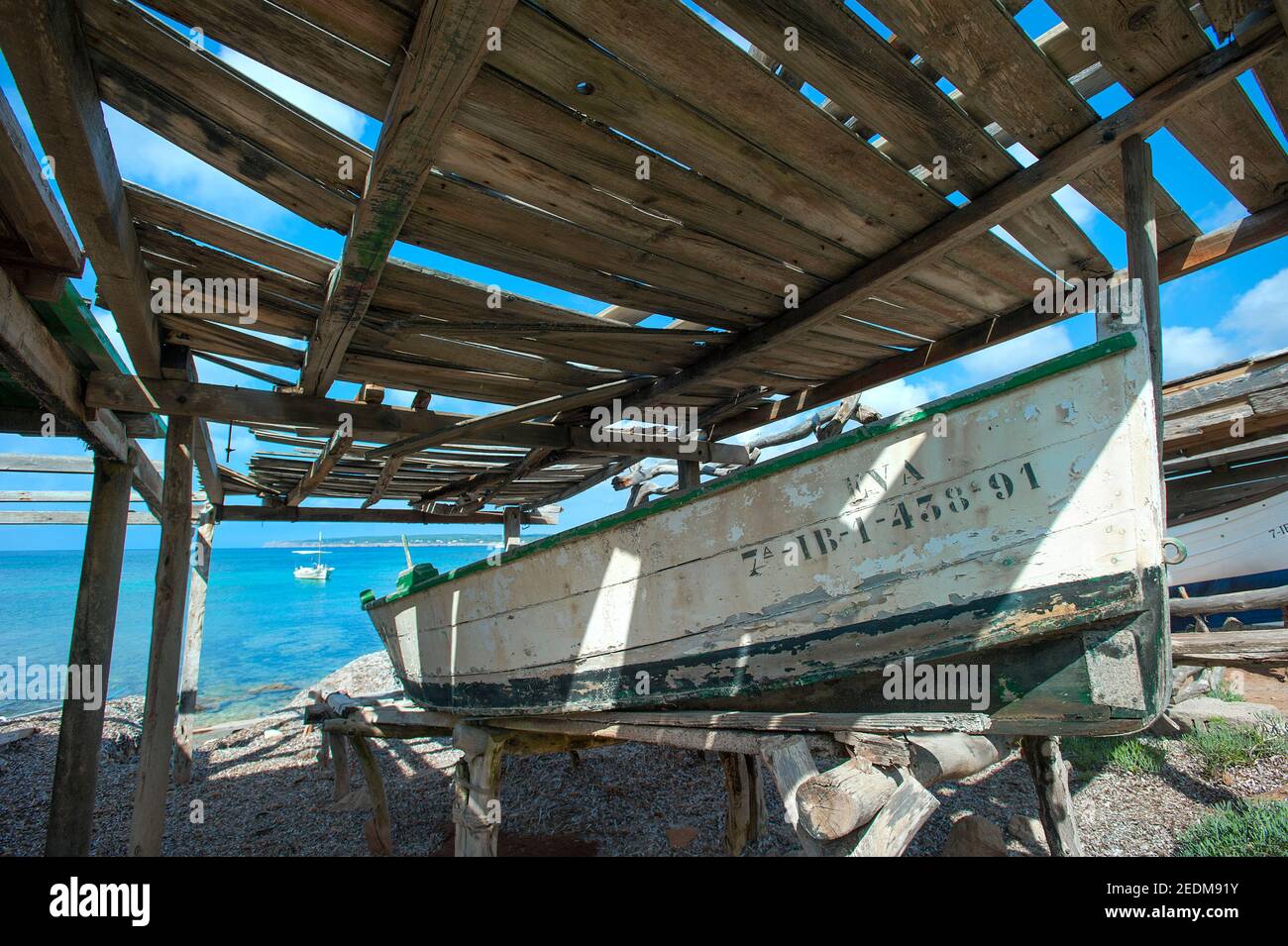 Fishing boat under wooden shelter, Playa Mitjorn, Formentera, Balearics, Spain Stock Photo