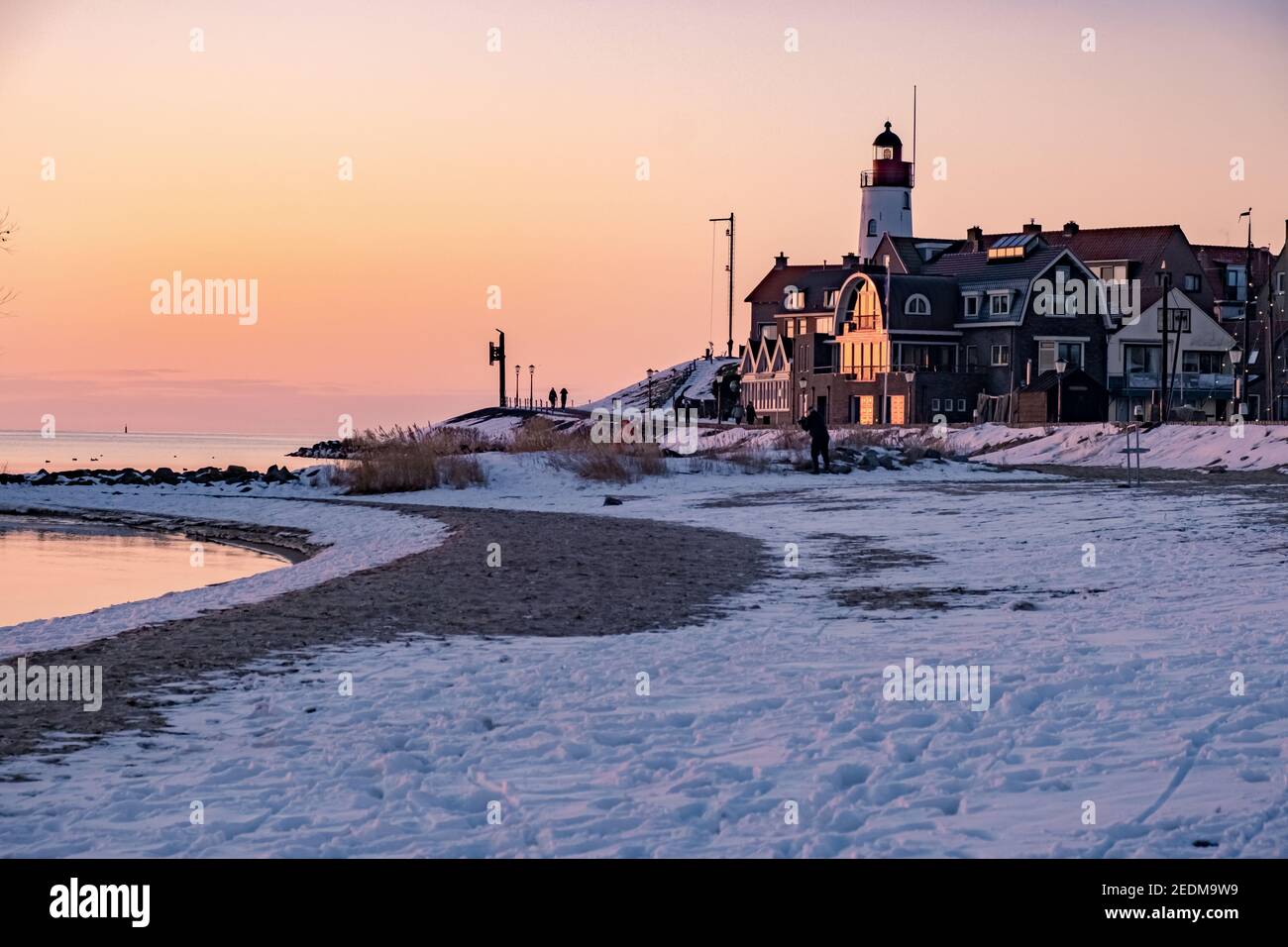 snow covered beach during wnter by Urk lighthouse in the Netherlands