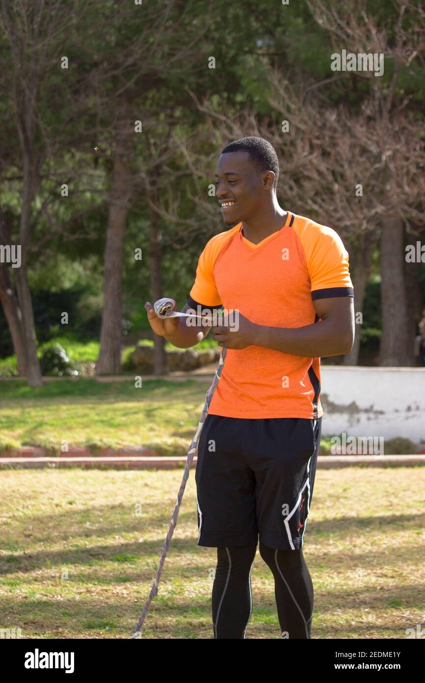 Black professional boxer puts on boxing bandages while he is resting from boxing training outdoors. Boxing and Training Concept 2021. Stock Photo