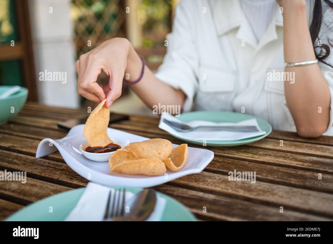 Woman having thai prawn crackers appetizer before meal in the Thai food restaurant Stock Photo